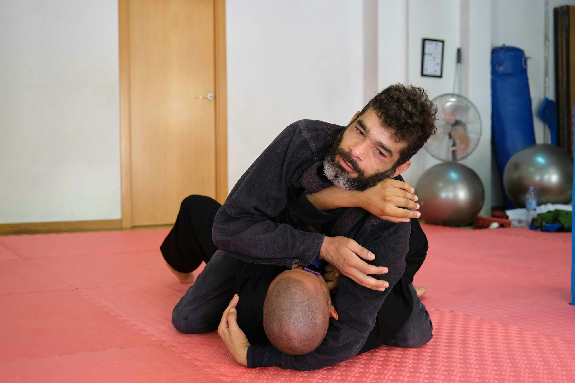 Two men practicing Brazilian Jiu-Jitsu sparring at the School.